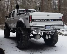 a white truck parked in the snow next to trees