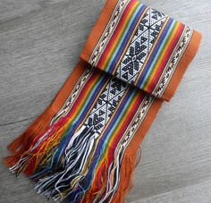 an orange and multicolored blanket laying on top of a wooden floor