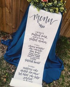 a menu sitting on top of a blue cloth next to a wooden fence with flowers