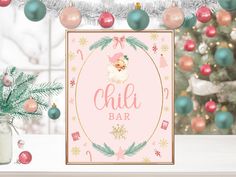 a pink and gold christmas themed bar sign next to a tree with ornaments on it