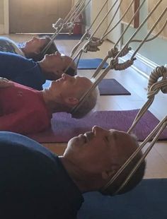 two women are laying on their stomachs in yoga mats with ropes attached to them