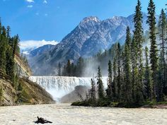 there is a large waterfall in the distance with trees around it and mountains in the background