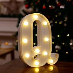 a lighted letter sitting on top of a table next to a christmas tree