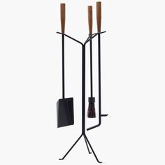 a metal and wood candle holder with two candles on it's legs, one holding a broom and the other carrying a black bag