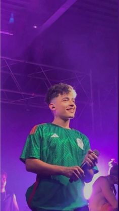 a young man standing in front of a purple light