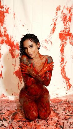 a woman covered in blood sitting on the ground with her arms crossed over her chest