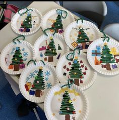 paper plates decorated with christmas trees and presents are on a table in front of children's chairs