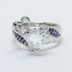 a heart shaped diamond ring with blue sapphire accents