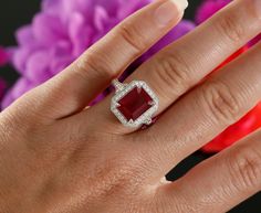 a woman's hand with a ring on it and a red stone in the middle