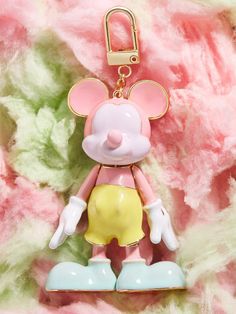 a pink and yellow mouse ornament hanging from a chain on a flowery background