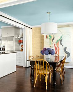 a dining room table and chairs in front of an open kitchen door with blue paint on the walls