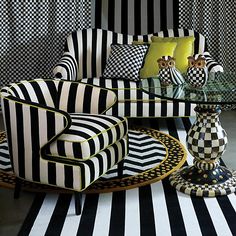 a black and white striped living room with two chairs, a coffee table and vases