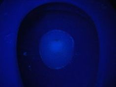 a blue toilet with the lid up and light shining on it's back side