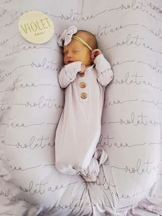 a baby sleeping on top of a white pillow next to a round object that says violet