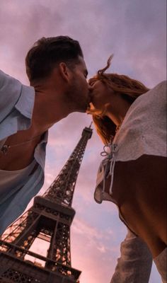 a man and woman kissing in front of the eiffel tower