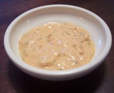 a white bowl filled with sauce on top of a wooden table