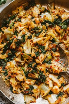 a skillet filled with stir fry vegetables on top of a table