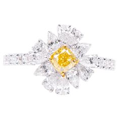 Welcome to the epitome of elegance—the 18 Karat Gold 2.706 Carat Fancy Yellow Diamond and Diamond Flower Ring. Our skilled artisans have meticulously crafted this piece, ensuring that each ring is a unique representation of timeless beauty. At the heart of this exquisite ring lies a floral design, brought to life with a meticulously curated collection of diamonds totaling 2.706 carats. These diamonds are thoughtfully arranged to resemble delicate petals, forming a bloom of unmatched brilliance a Luxury Yellow Gold Diamond Flower Ring, Luxury Yellow Gold Flower Ring With Diamonds, Luxury Yellow Gold Flower Ring With Diamond Accents, Luxury Flower Shaped Brilliant Cut Diamond Ring, Luxury Diamond Flower Ring For Formal Occasions, Luxury Diamond Flower Ring For Formal Events, Elegant Yellow Flower Shaped Ring, Luxury Diamond Flower Ring With Prong Setting, Luxury Flower Shaped Diamond Ring