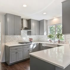 a kitchen with gray cabinets and white counter tops, wood floors and hardwood flooring