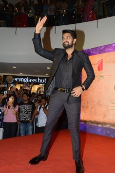 a man standing on top of a red carpet in front of a group of people