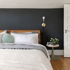 a bedroom with black walls and white bedding