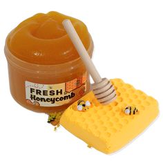 a honeycomb with a wooden stick and a jar of fresh honey on the side