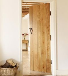 an open wooden door in a hallway with a basket on the floor next to it