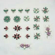 many different types of brooches on a white surface with one being pink and the other is green