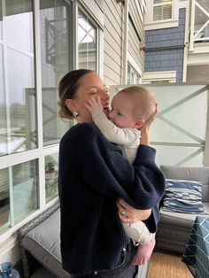 a woman holding a baby in her arms and looking out the window at something outside