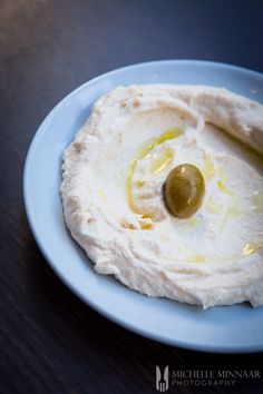 hummus with olives on a blue plate