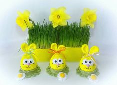 three crocheted easter eggs sitting in front of daffodils and grass