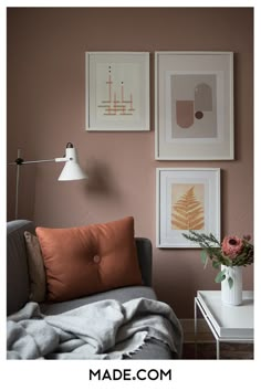 a living room with pink walls and pictures on the wall, including an orange throw pillow