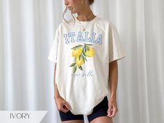 Trendy Italia "ciao bella' lemon graphic shirt for women. Great for an Italian girl's trip or travel souvenir shirt. Available in the colors Ivory, Pepper, Mustard, Black & Blue Jean. Relaxed unisex fit. True to size. Size up for an oversize look.  ~made with 100% ethically grown, ring-spun US cotton for long-lasting comfort. ~relaxed fit  ~pre-shrunk fabric ensures a consistently great fit All t-shirts are made to order and can only be refunded if damaged or incorrect. Please message me before White Crew Neck T-shirt With Lemon Print, Yellow Lemon Print Crew Neck Top, Yellow Crew Neck Top With Lemon Print, Casual Crew Neck Top With Lemon Print, Short Sleeve Lemon Print Graphic Tee, White Short Sleeve Top With Lemon Print, Cotton Graphic Tee With Lemon Print, Cotton T-shirt With Lemon Print, Short Sleeve, White Short Sleeve T-shirt With Lemon Print