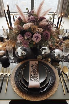 a table set with black and gold plates, silverware and flowers in the center