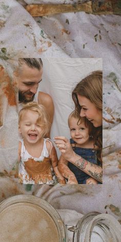 two adults and a child sitting on top of a bed next to an old clock