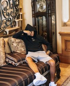 a man sitting on top of a couch in front of a grandfather's clock