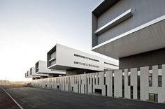 an empty parking lot in front of a building with many windows on the side of it