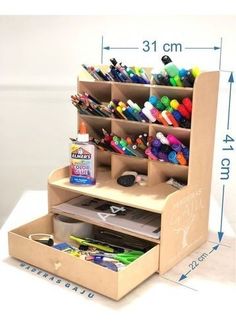 an open cardboard box with pens, markers and pencils in it on a table