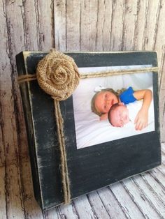 an old photo frame with a twine and rope attached to it, sitting on a wooden surface