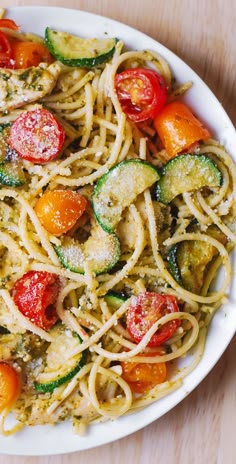 a white bowl filled with pasta and veggies on top of a wooden table