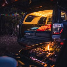 a camper van with the back door open and food on the grill in the bed