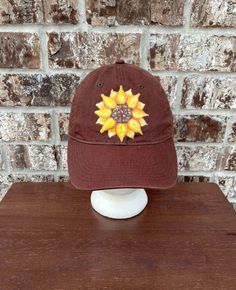 "Authentic Pigment cotton baseball cap in brown with a hand painted sunflower.  Washed multiple times for a unique faded look 100% cotton twill 6-panel, unstructured sewn eyelets self-fabric closure with D-ring slider and tuck-in strap One Size Hat Band 22.8\" These are great hats! My family has worn them for years. I wash them in cold water on the gentle cycle. Visit my new glassware shop https://www.etsy.com/shop/kitchenbarhomedecor for unique gifts for your home! Follow me on Instagram http://www.instagram.com/gulflifebynichole" Brown Cotton Dad Hat With Curved Brim, Brown Cotton Trucker Hat With Curved Bill, Brown Cotton Trucker Hat One Size, Brown Country Style Baseball Cap With Curved Brim, One Size Brown Cotton Trucker Hat, Brown Cotton Baseball Cap, Brown Cotton Dad Hat, Brown Cotton Brimmed Baseball Cap, Brown Dad Hat With Curved Brim