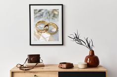 two gold wedding rings sitting on top of a wooden dresser