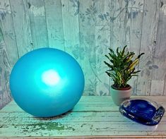 a large blue ball sitting on top of a wooden table next to a potted plant