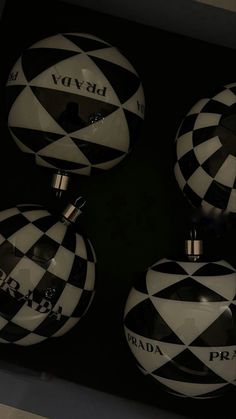 three black and white round ornaments with the word prada written on them in cursive letters