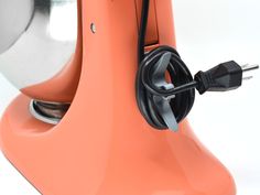 an orange mixer with a black cord plugged in to it's outlets