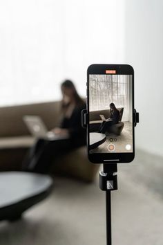 a person sitting on a couch using a cell phone to take a photo with their laptop