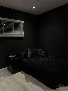 a bedroom with black walls and wooden floors, dark bedding, and white flooring