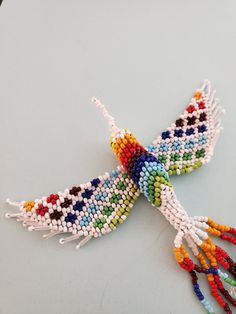 a multicolored beaded bird is sitting on a table with it's wings spread out