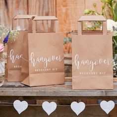 three brown paper bags sitting on top of a wooden table next to vases and flowers